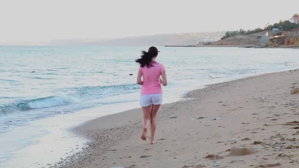 Ragazza che corre su una spiaggia sulla costa del mare — Video Stock