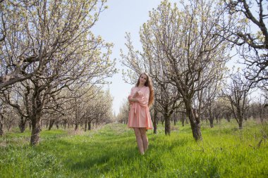 bir çiçek bahçesi ile şeftali elbiseli kız yürüyor