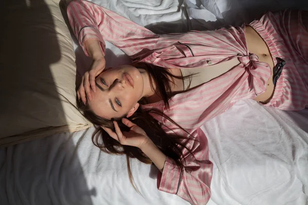 Όμορφη γυναίκα σε ροζ πιτζάμες στην κρεβατοκάμαρα — Φωτογραφία Αρχείου
