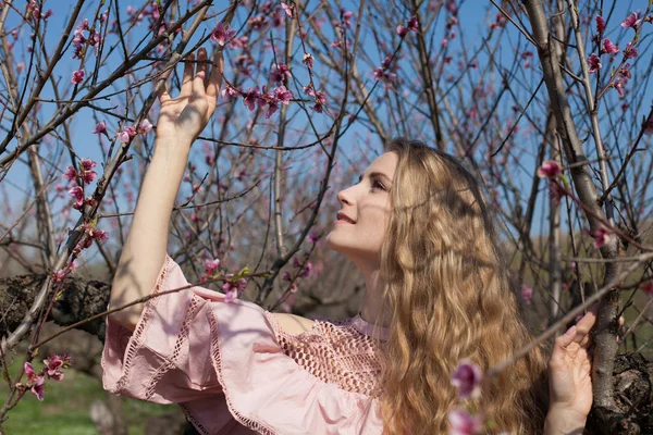 Menina loira em vestido rosa está coletando flores no jardim — Fotografia de Stock