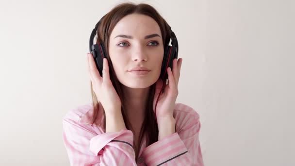 Femme en pyjama est couché danse à la musique de écouteurs — Video