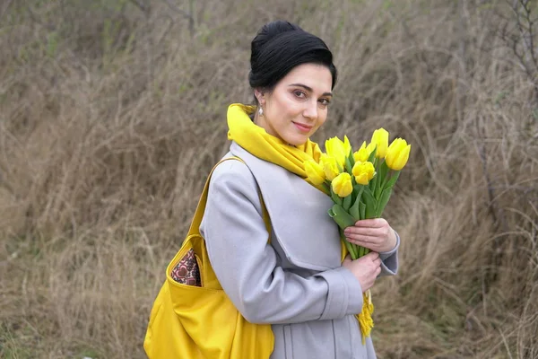 Retrato de morena em casacos com tulipas amarelas — Fotografia de Stock