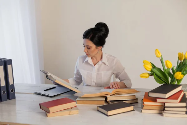 Mujeres en un traje de negocios detrás de una mesa con libros — Foto de Stock