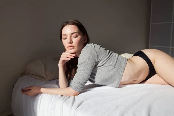 Yatak odasında yatağın üzerinde iç çamaşırı esmer kadın yatıyor — Stok fotoğraf