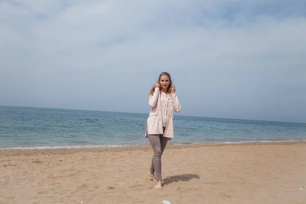 Blonde girl walking on a sandy beach sea shore — Stock Photo, Image