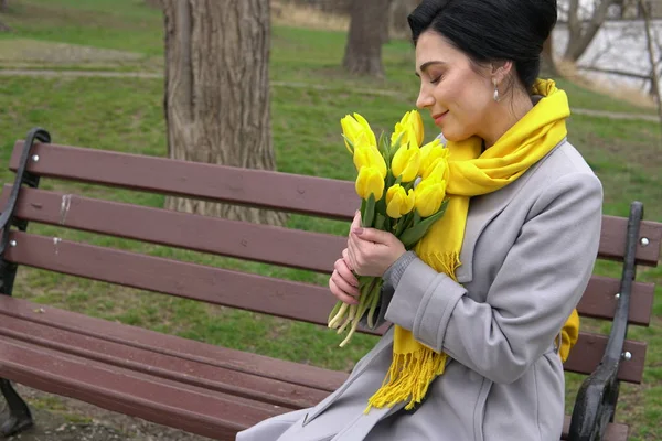 Brünette Frau in Mänteln mit gelben Tulpen — Stockfoto