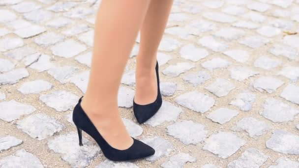 Frauenbeine in schwarzen Schuhen auf einer steinigen Straße — Stockvideo