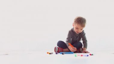 küçük çocuk renkli kalemler kağıt üzerinde çizer.