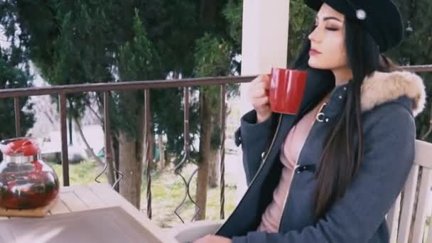 Beautiful brunette drinking hot tea in the street restaurant — Stock Video