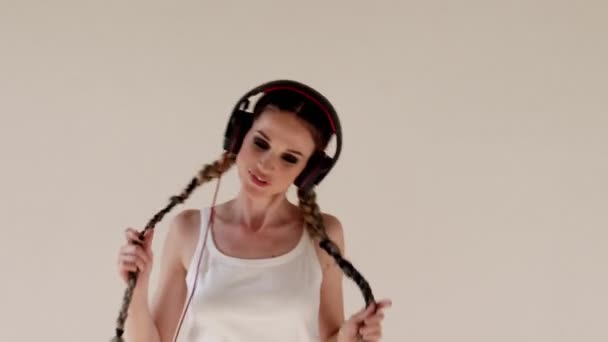 Una mujer con coletas escucha música con auriculares y bailando — Vídeos de Stock