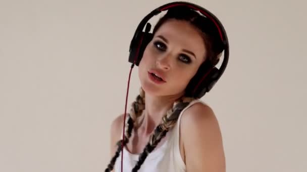 Een vrouw met pigtails luistert naar muziek met hoofdtelefoons en dansen — Stockvideo