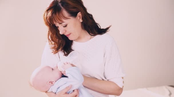 Moeder is het voeden van de baby melk uit een fles — Stockvideo