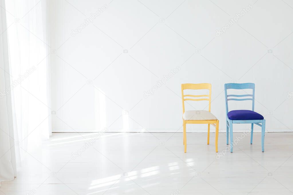 two chairs blue and yellow in the interior of an empty white room