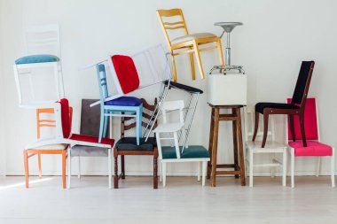 Beyaz odada bir sürü farklı sandalye var.