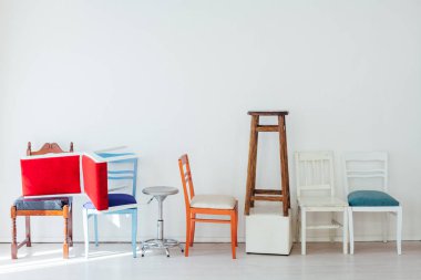 Beyaz odada bir sürü farklı sandalye var.