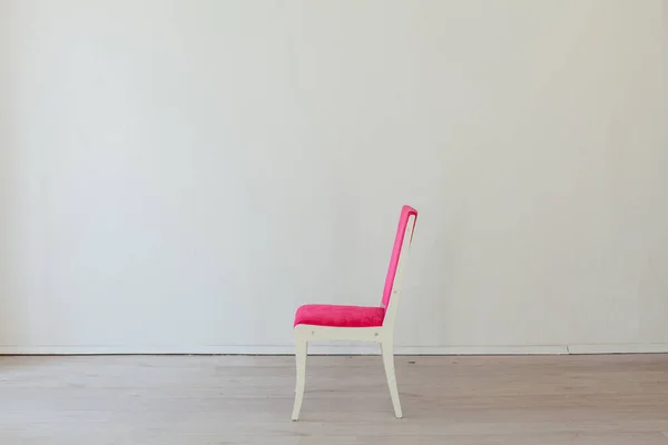 pink chair stands alone in the white room