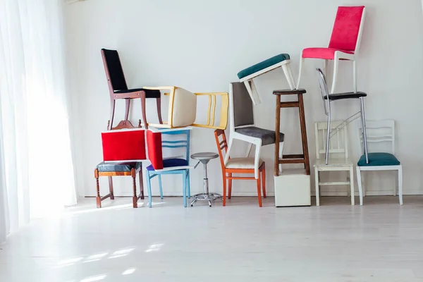 Many multicolored chairs stand in the white room — Stock Photo, Image