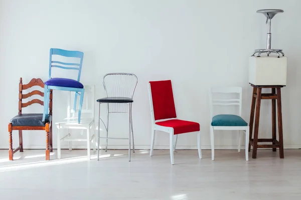 Molte sedie diverse stanno nella stanza bianca — Foto Stock
