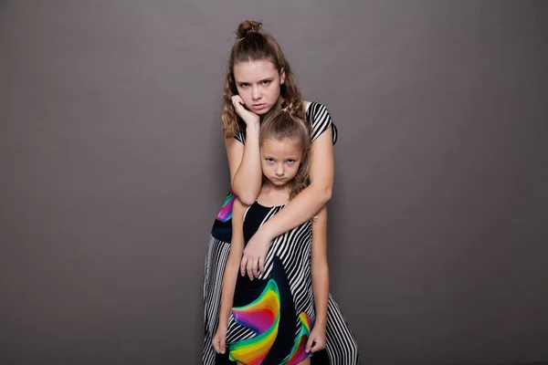 Portrait of two beautiful fashionable sisters girls on a gray background — Stock Photo, Image