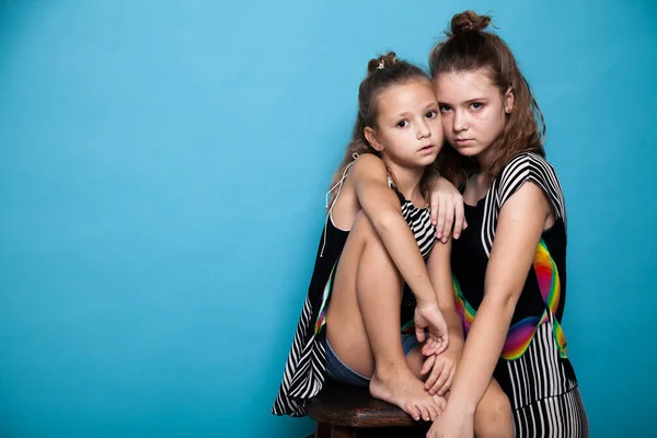 Portret van twee mooie modieuze zusjes meisjes op een blauwe achtergrond — Stockfoto