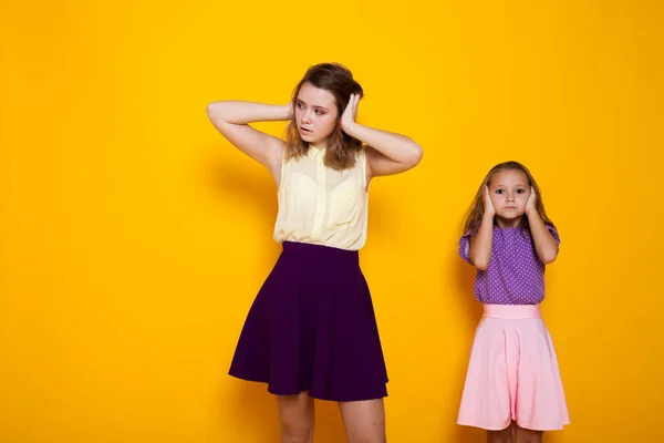 Ritratto di due belle sorelle alla moda di età diverse su uno sfondo giallo — Foto Stock