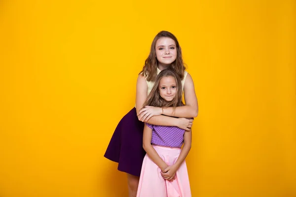 Portret van twee mooie modieuze zussen van verschillende leeftijden op een gele achtergrond — Stockfoto
