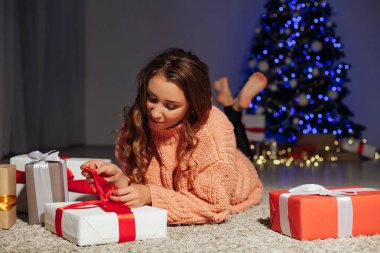 Güzel bir kadın Noel ağacında hediyeler açar. Yılbaşı süsleri.