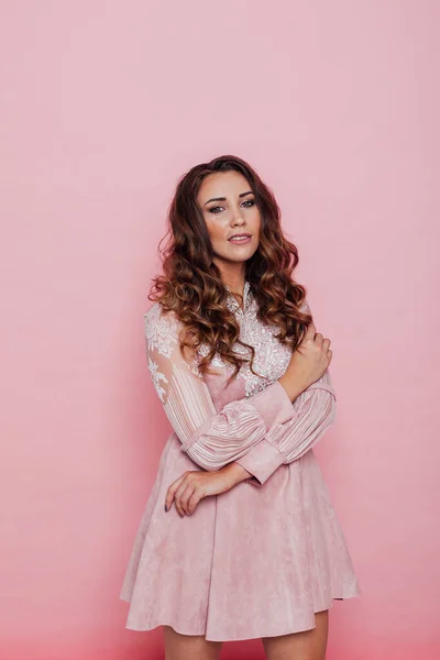 Retrato de una hermosa mujer de moda con rizos en un vestido rosa —  Fotos de Stock