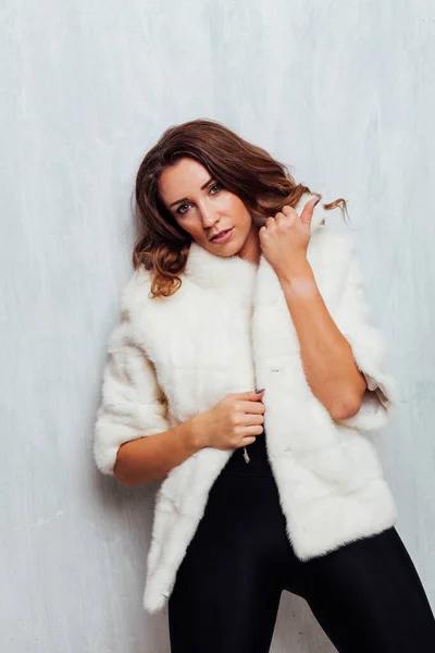 Retrato de una hermosa mujer de moda con rizos en un abrigo de piel blanca — Foto de Stock