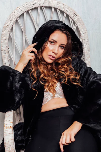 Portrait of a beautiful fashionable woman with curls in a black fur coat — Stock Photo, Image