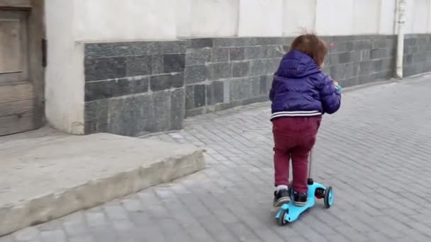 Criança monta uma scooter em um parque. Infância despreocupada — Vídeo de Stock