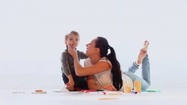 Anne küçük bir çocukla oynuyor ve odada çizim yapıyor.