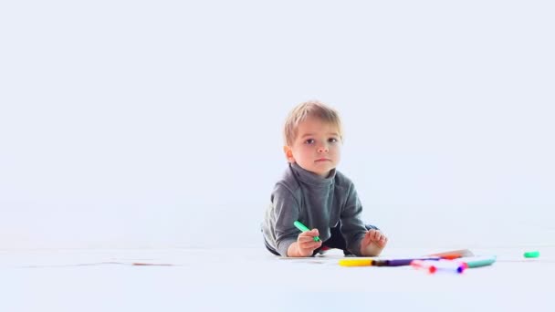 Niño pequeño pinta cuadros con marcadores de color en el suelo — Vídeos de Stock