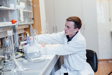 Erkek bilim adamı tıp bilimi laboratuvarında kimyasal deneyler yapıyor.