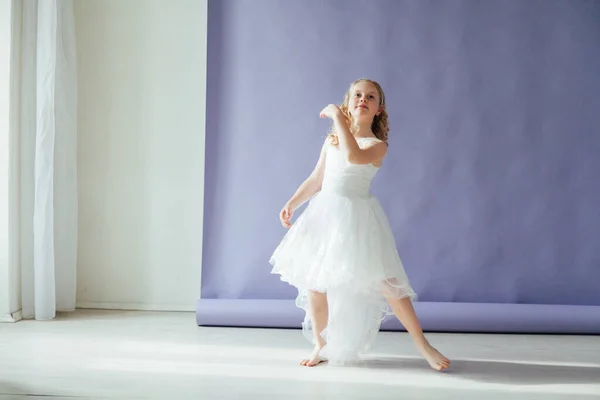 10 yıllık güzel bir kız beyaz bir elbiseyle dans ediyor. — Stok fotoğraf