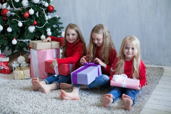 Tres niñas abren regalos en el árbol de Navidad de año nuevo de invierno — Foto de Stock