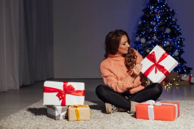 Noel ağacında bukleli güzel bir kadının portresi Yeni yıl hediyeleriyle süslenmiş çelenk.