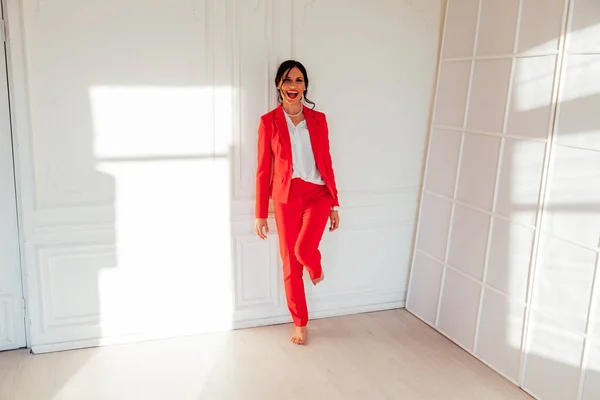 Retrato de uma mulher de negócios morena em um terno de negócios vermelho no escritório — Fotografia de Stock