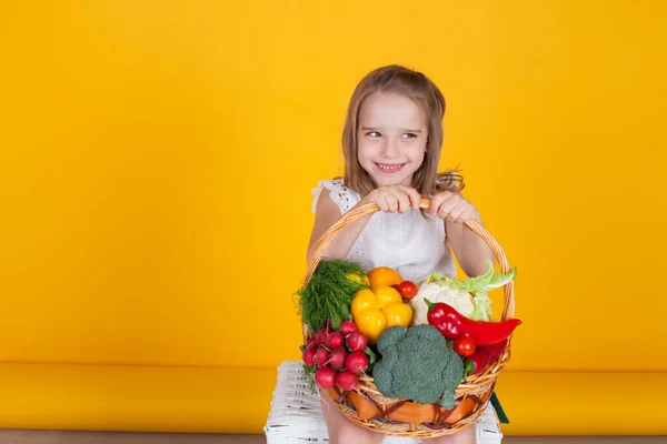 Little girl holds a basket of ripe vegetables — Stock Photo, Image