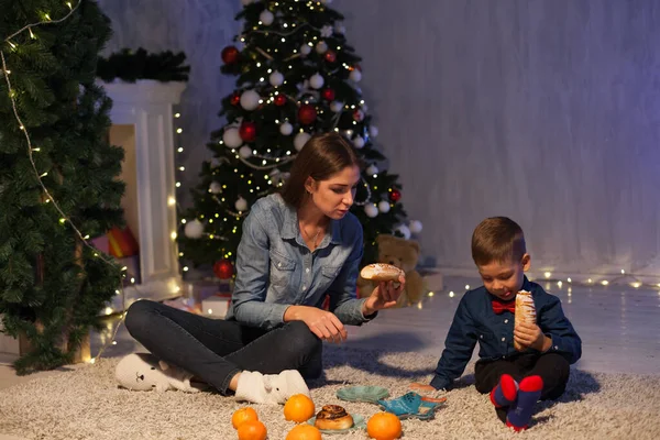 Beautiful mom with son at christmas tree with new year decor gifts