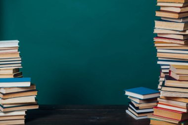 Kütüphanedeki duvarın arka planına karşı eğitim kitapları yığını