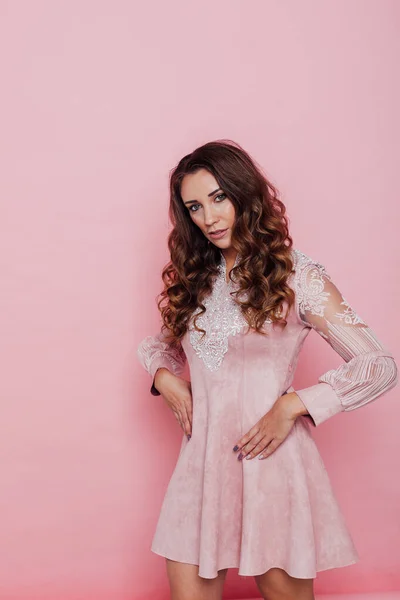 Portrait of a beautiful fashionable woman with locks in a pink dress