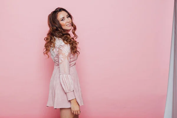 Portrait of a beautiful fashionable woman with locks in a pink dress