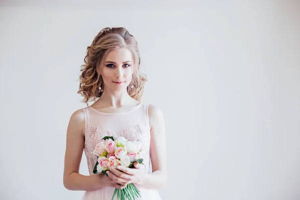 Noiva em vestido de noiva segurando um buquê de flores — Fotografia de Stock