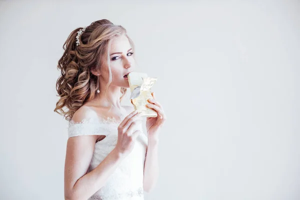 Noiva em vestido de noiva segurando um chocolate — Fotografia de Stock