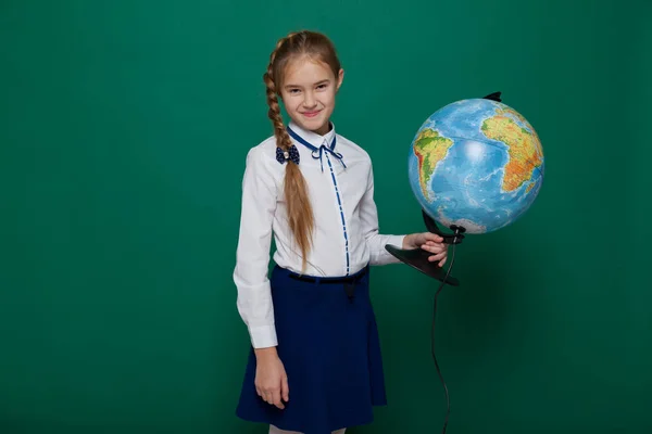 Girl school with globe to study stands at the green board in class — Stock Photo, Image