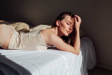 Yatak odasında yatağın üstünde gri iç çamaşırı esmer kadın yatıyor