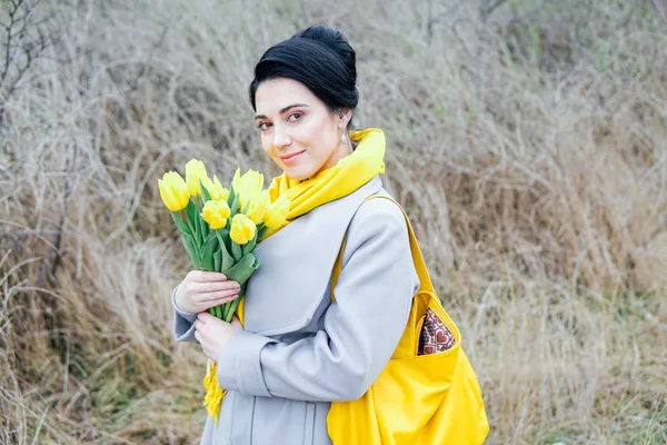 Retrato de morena em casacos com tulipas amarelas — Fotografia de Stock