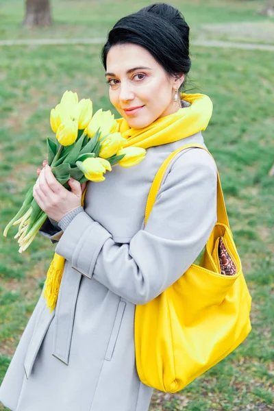 Porträt einer Brünetten in Mänteln mit gelben Tulpen — Stockfoto