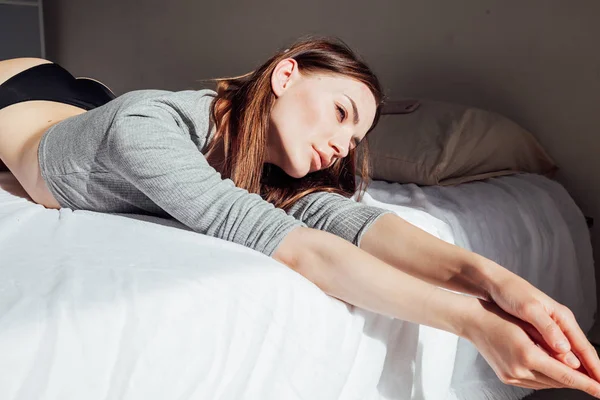 Brünette Frau in Unterwäsche liegt auf dem Bett im Schlafzimmer — Stockfoto